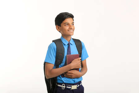 Indian school boy in uniform and holding diary in hand on white background.の写真素材