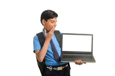 Indian school boy showing laptop screen on white background.の写真素材