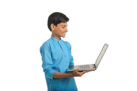 Technology concept : Cute indian little school boy using laptop