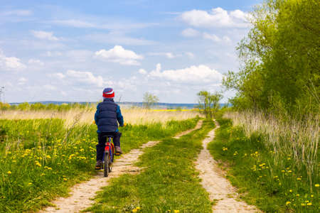 Boy on bike on country road sunny spring dayの写真素材