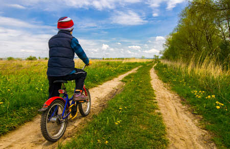Boy on bike on country road sunny spring dayの写真素材