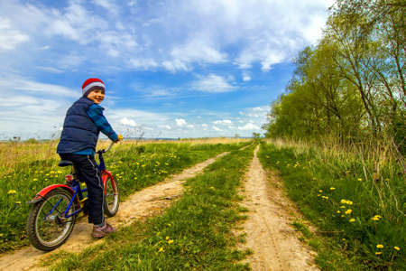 Boy on bike on country road sunny spring dayの写真素材