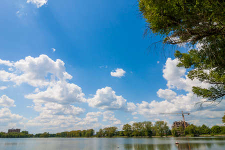 Clear lake reflecting blue sky with puffy white clouds in bright sunny dayの写真素材