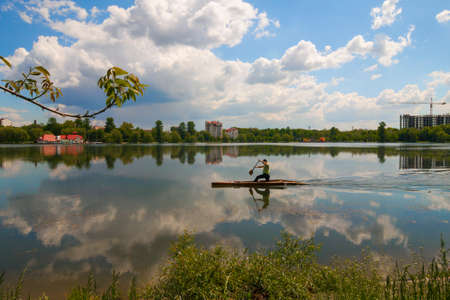 Man is rowing on a kayak boat on city lake on a sunny dayの写真素材