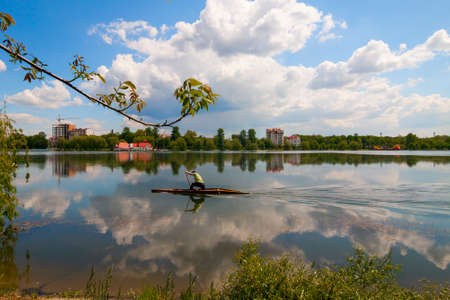 Man is rowing on a kayak boat on city lake on a sunny dayの写真素材