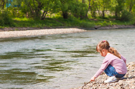 Little girl playing near riverの写真素材
