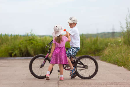 Two children in summer day bicycle and flower boy and girlの写真素材