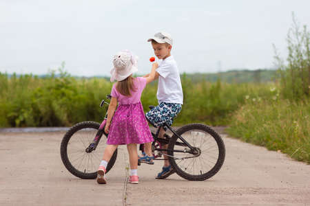 Two children in summer day bicycle and flower boy and girlの写真素材