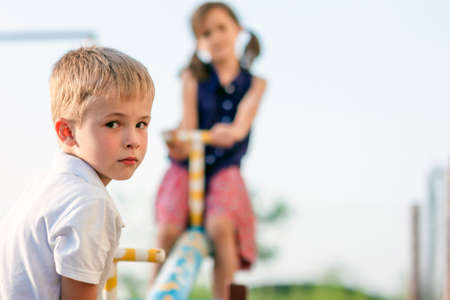 Children playing on swing. Boy in focus and girl blurred behind.の写真素材
