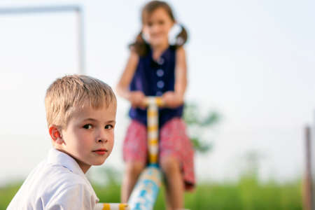 Children playing on swing. Boy in focus and girl blurred behind.の写真素材