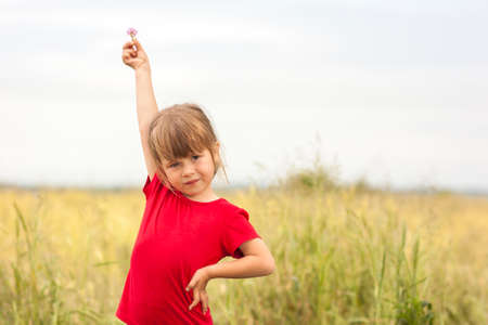 Cute little smiling girl holding little flower up in handの写真素材