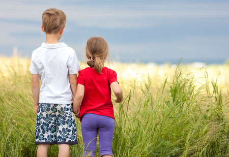 Little boy and little girl standing holding hands looking on horizontの写真素材