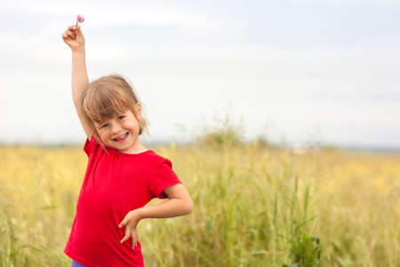 Cute little smiling girl holding little flower up in handの写真素材