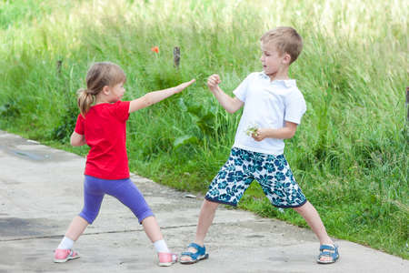 Children playing fighting on sunny summer dayの写真素材