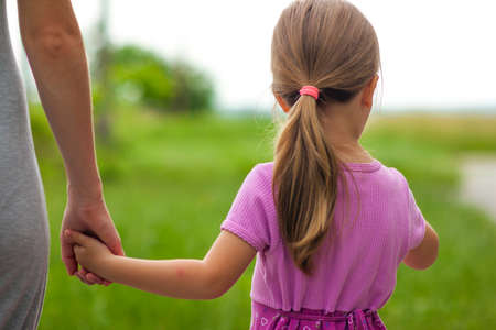 Little girl holding a hand of her mother. Family relations concept.の写真素材