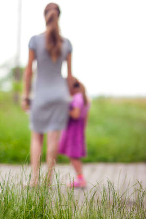 Silhouette of little girl holding a hand of her mother. Family relations concept.の写真素材