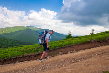 Hiker climbing up mountain in summer sunny dayの写真素材