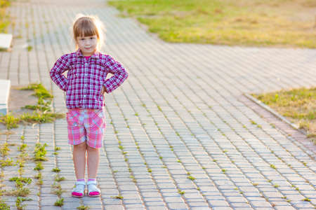 Little girl on summer day standing with hands on hipsの写真素材