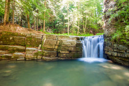 Little waterfall in mountain forest with silky foaming waterの写真素材