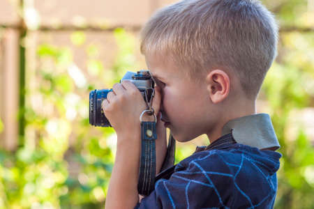 Cute little happy boy with vintage photo camera outdoorsの写真素材