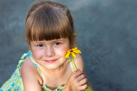 Cute smiling little girl holding yellow flowerの写真素材