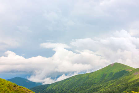 Sharp green mountain peaks and sky with dramatic clouds landscapeの写真素材