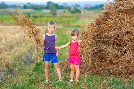 Little boy and girl on field near haystackの写真素材