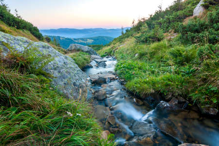 Beautiful little waterfall in mountains with white foamy silky waterの写真素材