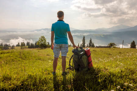 Hiker with a backpack standing in mountainsの写真素材