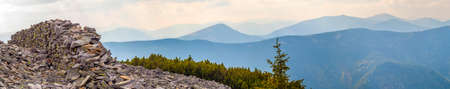Panorama of blue mountains with wall of stones and pine trees in viewの写真素材