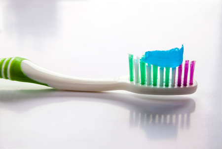 Toothpaste on a toothbrush close-up on a white light backgroundの写真素材