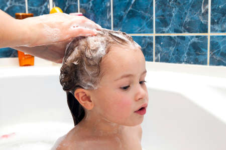Mom's hands washing little girly's head in the bathroom. The symbol of purity and hygiene education.