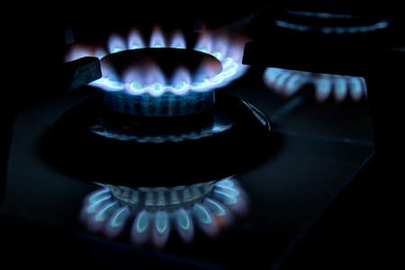 Burning gas stove hob blue flames close up in the dark on a black backgroundの写真素材