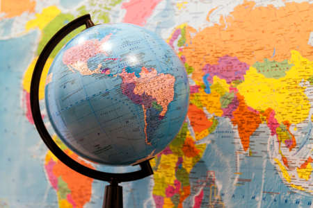 Closeup of a globe with asia and africa and a world map with north and south america on the wall in classroomの写真素材