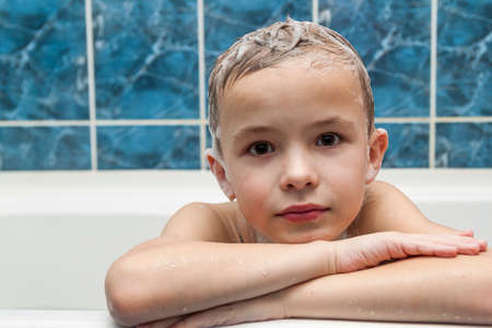 Adorable baby boy with shampoo soap suds on hair taking bath. Closeup portrait of smiling kid, health care and hygiene concept . Isolated on white and blue background with clipping path.の写真素材