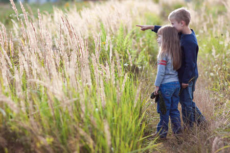 Little boy and little girl standing holding hands looking on horizont. Rear view.の写真素材
