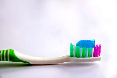 Toothpaste on a toothbrush close-up on a white light backgroundの写真素材