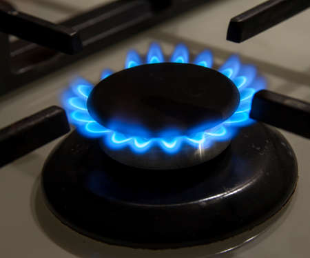 Burning gas stove hob blue flames close up in the dark on a black background