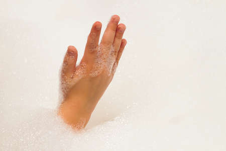 Childs hand in fshampoo foam in bath. Healthcare and hygiene concept.の写真素材