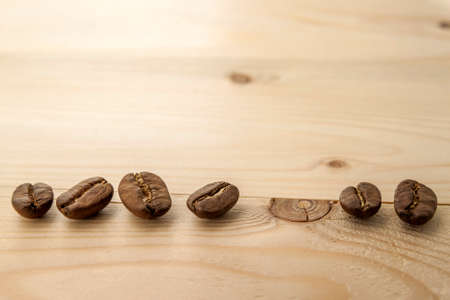 Brown coffee beans on yellow textured wooden board background close up.の写真素材