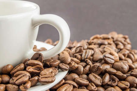 Cup of coffee in a white cup and coffee beans on wooden table background, top view.の写真素材
