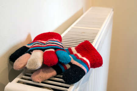 Childs knitted gloves drying on heating radiator after winter day outsideの写真素材