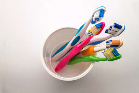 Close up shot of set of multicolored toothbrushes in glass on clean toilet on white background, concept dental.の写真素材
