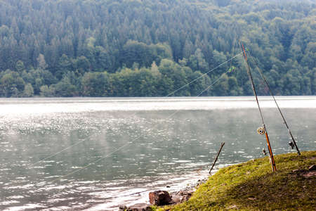 Fishing rod equipment on a lake in misty spring morningの写真素材