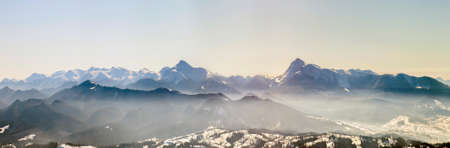 Beautiful winter panorama with fresh snow. Landscape with spruce pine trees, blue sky with sun light and high Carpathian mountains on background.の写真素材