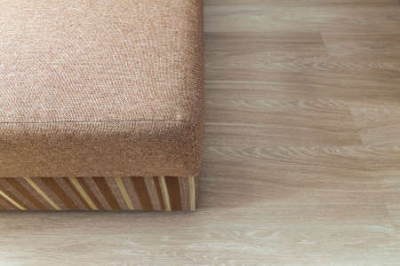Detail of a modern beige textured sofa in living room on wooden laminate parquet floorの写真素材