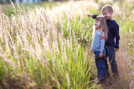 Little boy and little girl standing holding hands looking on horizont. Rear view.の写真素材