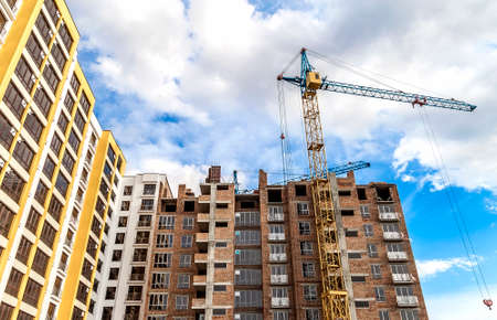 Crane and high rise building under construction against blue sky. Modern architecture background