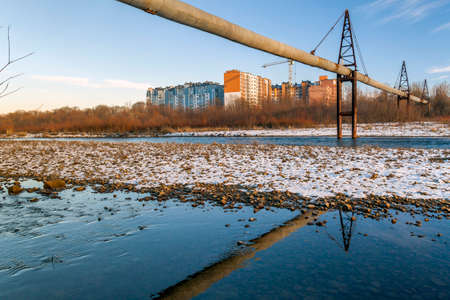 Gas or water pipe over the river and residential buildings behindの写真素材