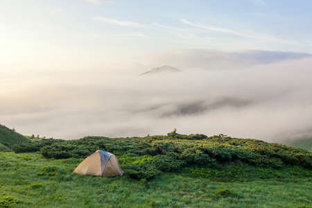 Panorama of cold foggy summer morning and tourist hikers tent in  Carpathian mountainsの写真素材